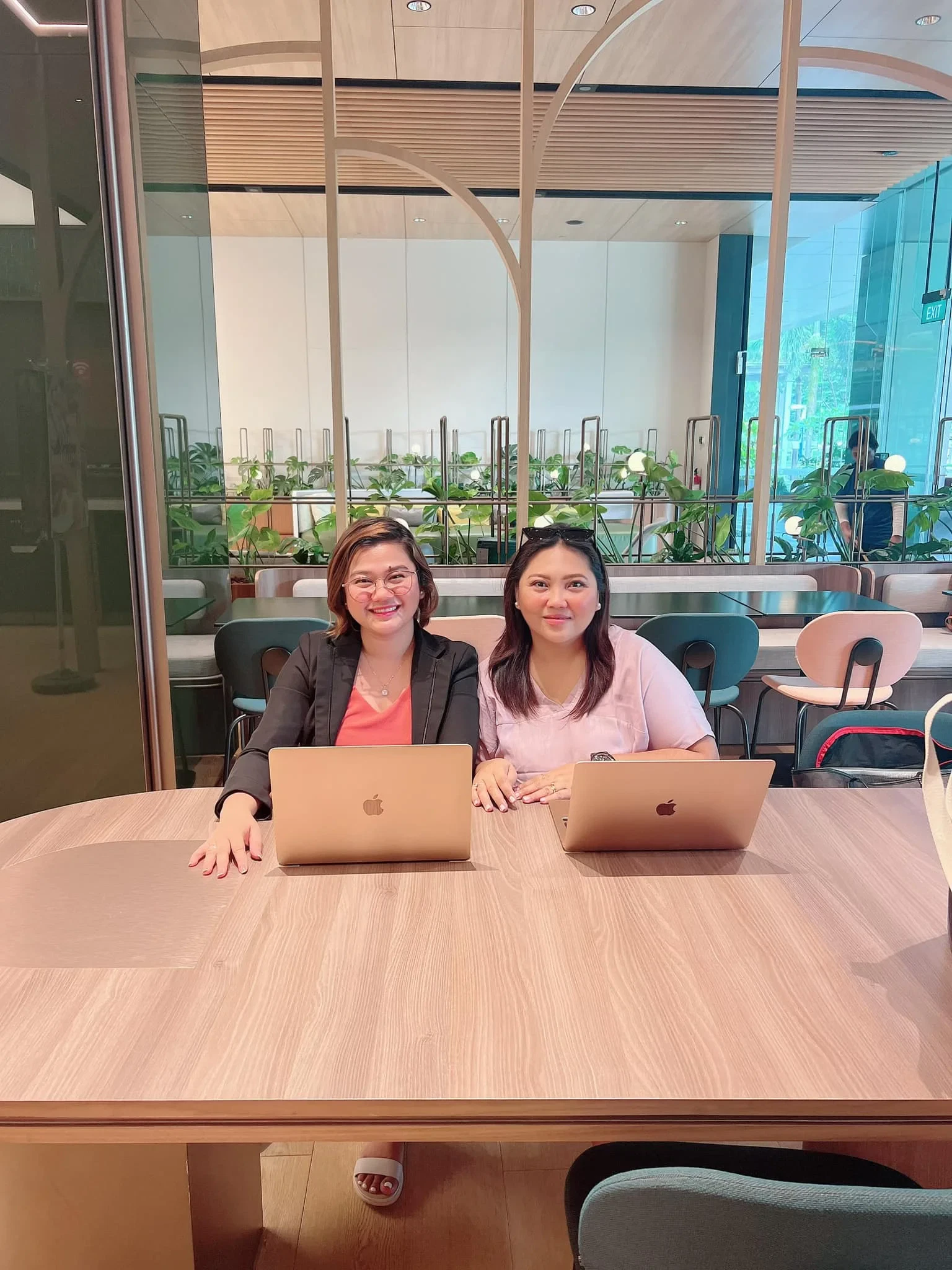 Two people seated at a table with laptops in a modern, well-lit room.